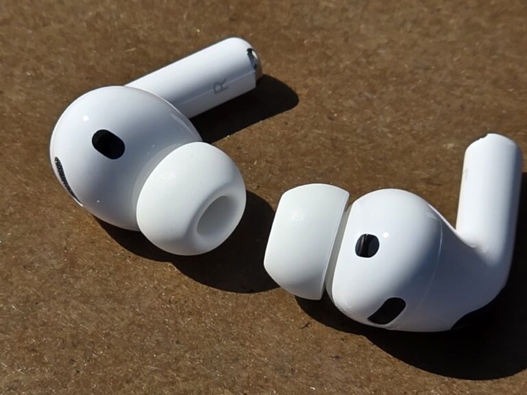 A closeup of a pair of Apple AirPods on a mottled brown surface.