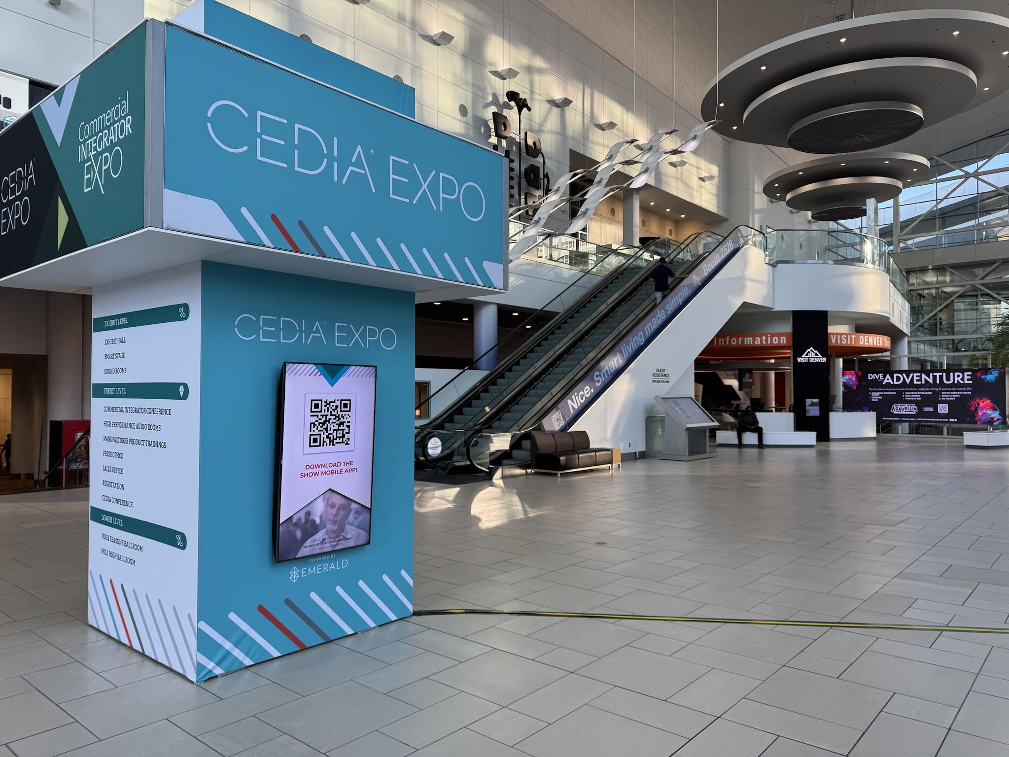 Pop-up sign on a convention center floor with aqua panels, white lettering reading "CEDIA EXPO" and almost no people visible.