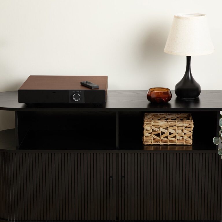 Walnut Victrola Soundstage powered speaker base positioned directly beneath a matching turntable on a wooden credenza